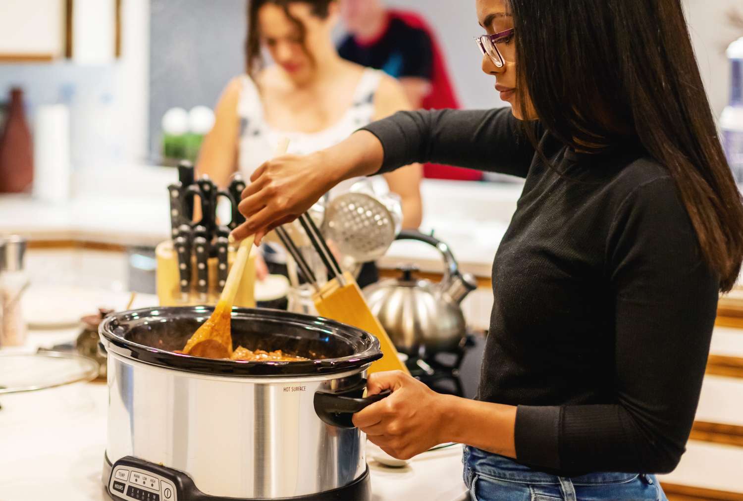 Hands stirring a slow cooker on a bright kitchen counter, with simple ingredients nearby and a cozy weeknight cooking vibe